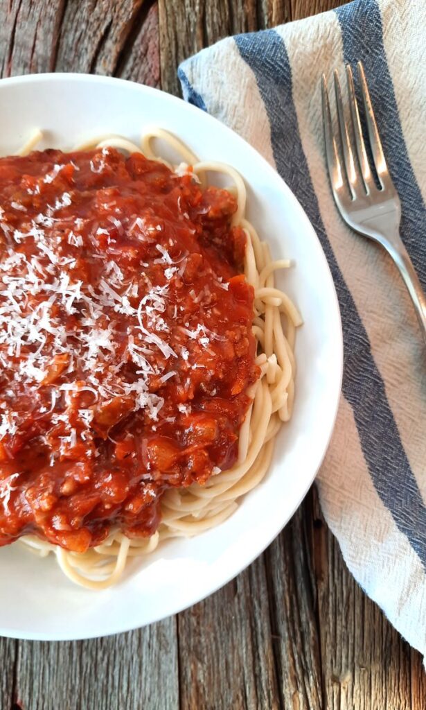 close up of spaghetti sauce piled on a bowl of spaghetti