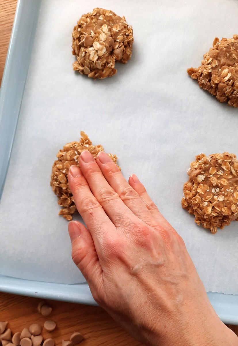 a hand presses down oatmeal cookie dough balls