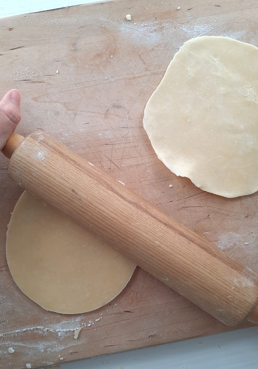 rolling pin rolling out the edges of a circle of pie crust