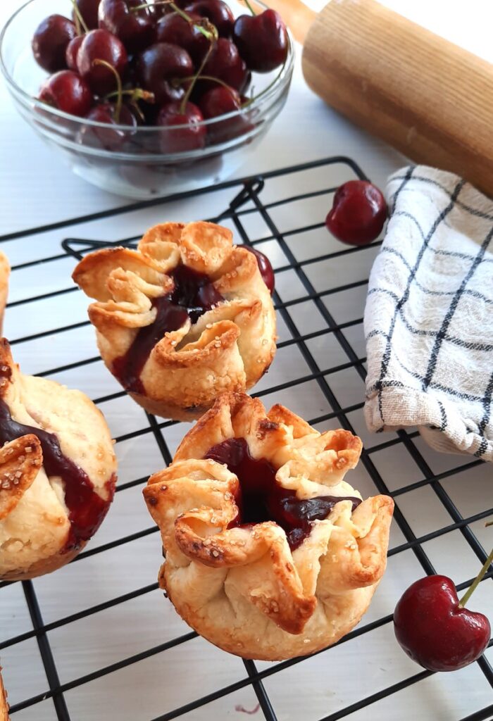 cherry pie rosettes cool on a metal cooling rack on a white kitchen counter