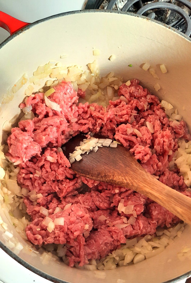 raw ground beef in a saucepan with onions