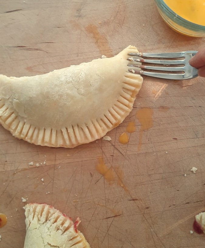 a fork presses down the edges of a hand pie