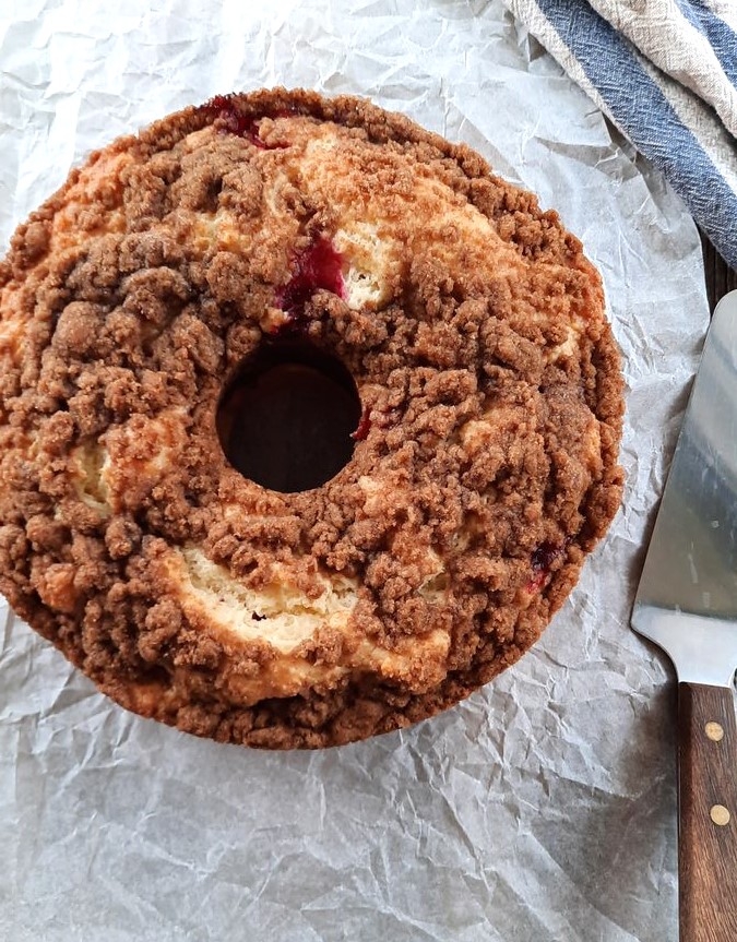 a full cranberry sour cream coffee cake sits on parchment paper