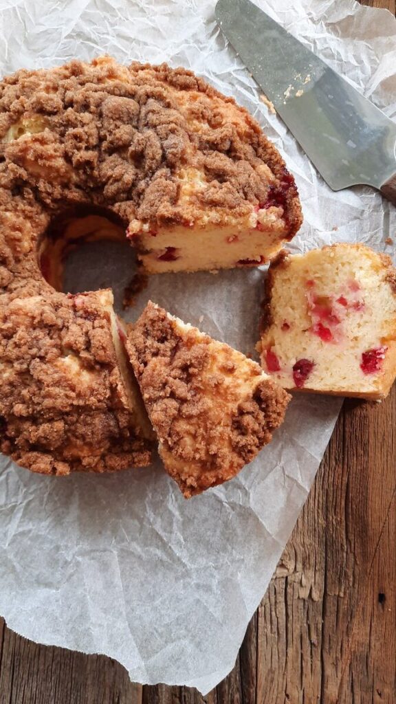 cranberry coffee cake with some slices cut out on a rustic table