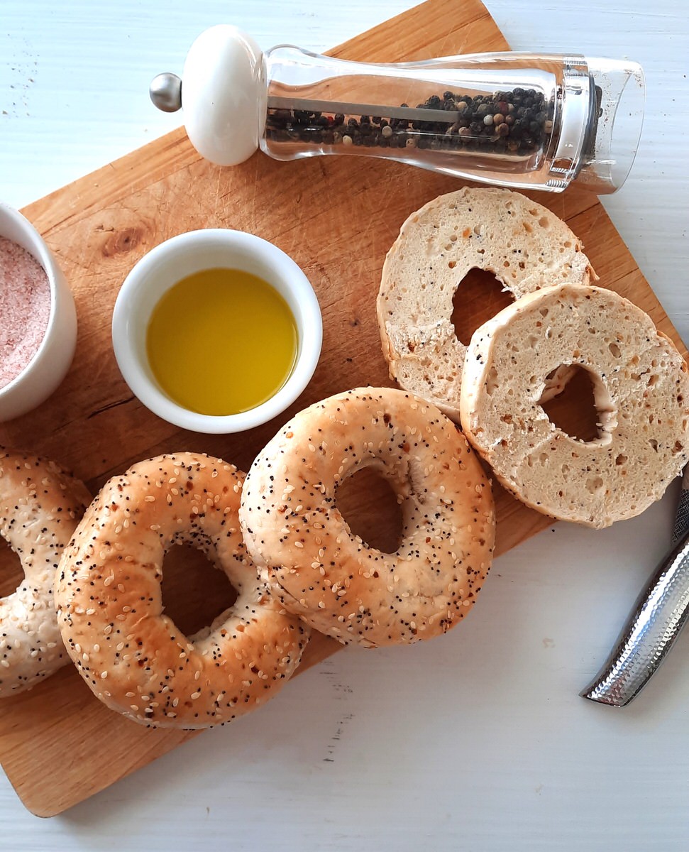 a cutting board covered in everything bagels, olive oil, salt, and pepper