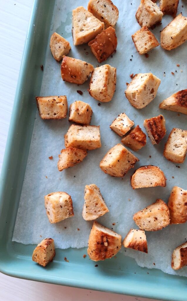 a baking sheet with freshly toasted bagel croutons