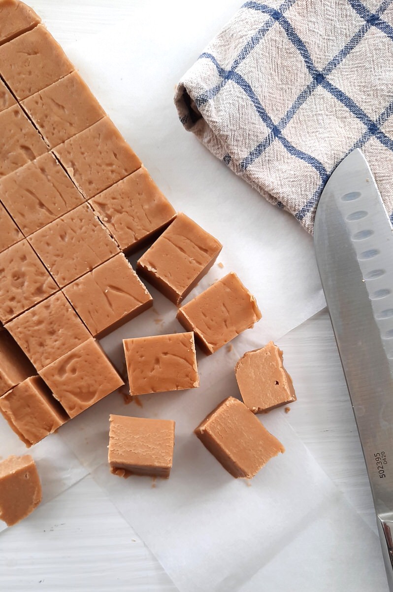 a knife sits beside a sheet of sliced up easy maple fudge