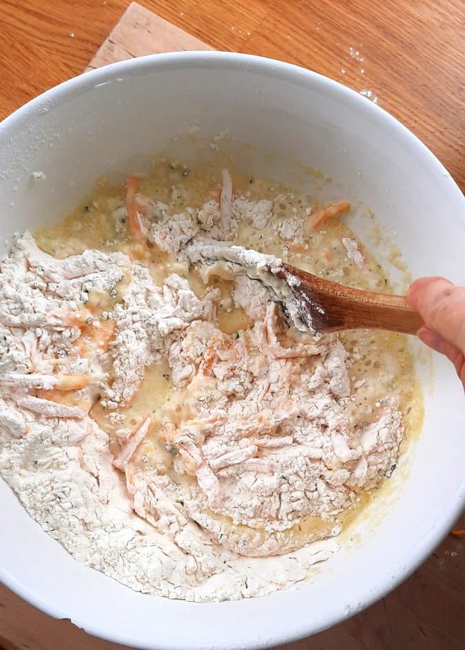 a wooden spoon stirs the wet ingredients into the dry ingredients to make fluffy Irish soda bread