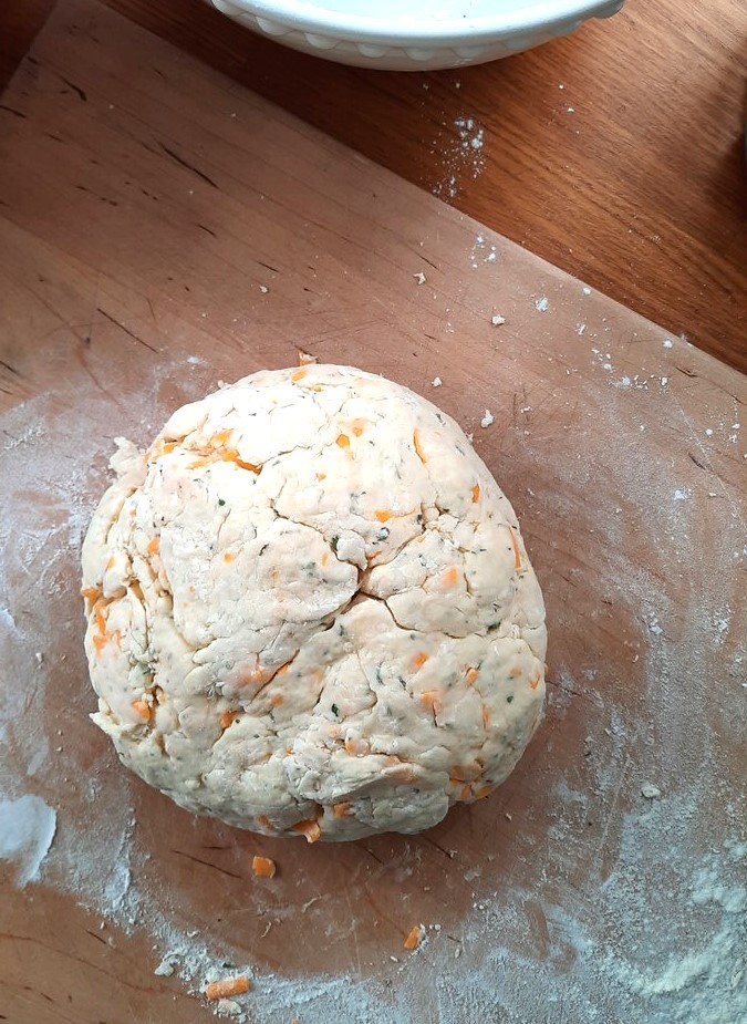 a ball of soda bread dough sits on a wooden cutting board