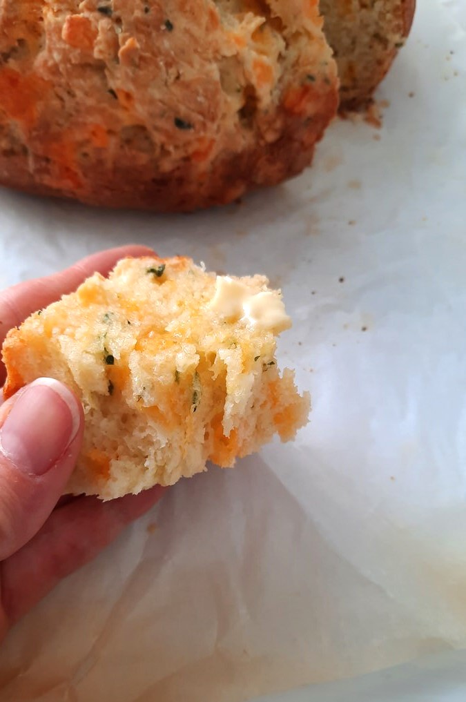a piece of Cheddar Irish Soda bread is held up to show its fluffy texture