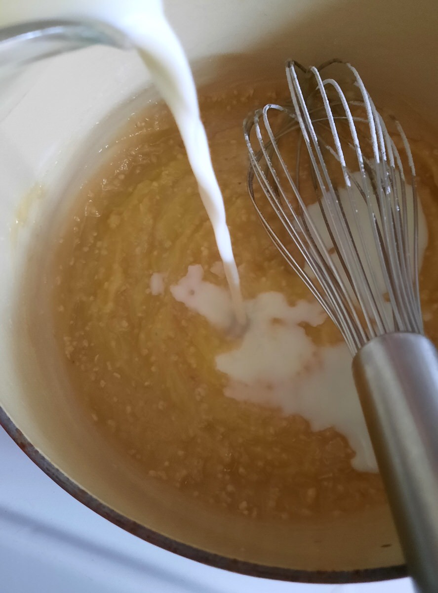 milk is poured into a saucepan of melted butter, flour, and garlic