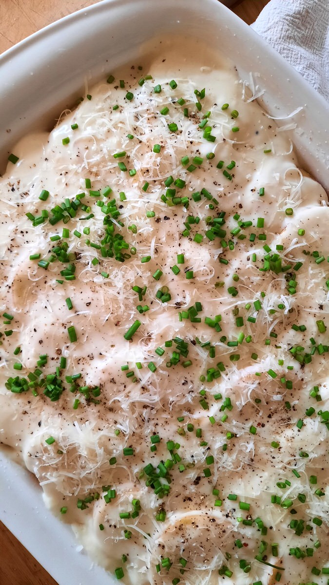 an uncooked dish of creamy scalloped potatoes ready to go into the oven
