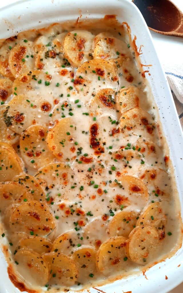 a large white casserole dish full of golden brown scalloped potatoes