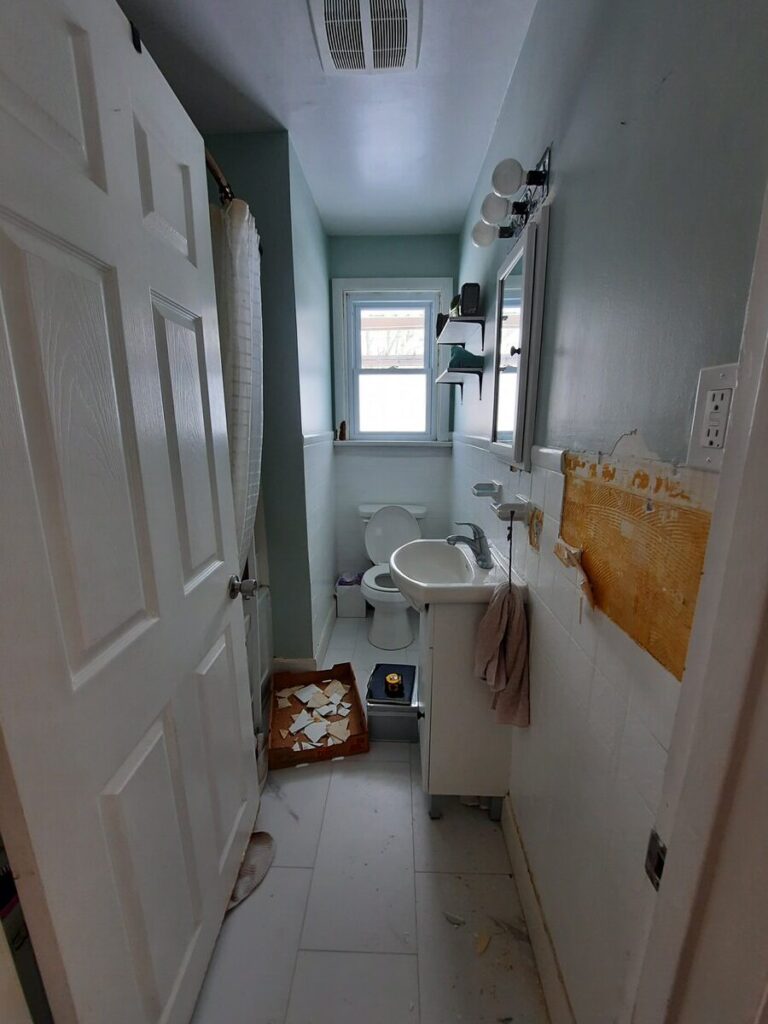 before photo of bathroom with broken tile and old light fixture
