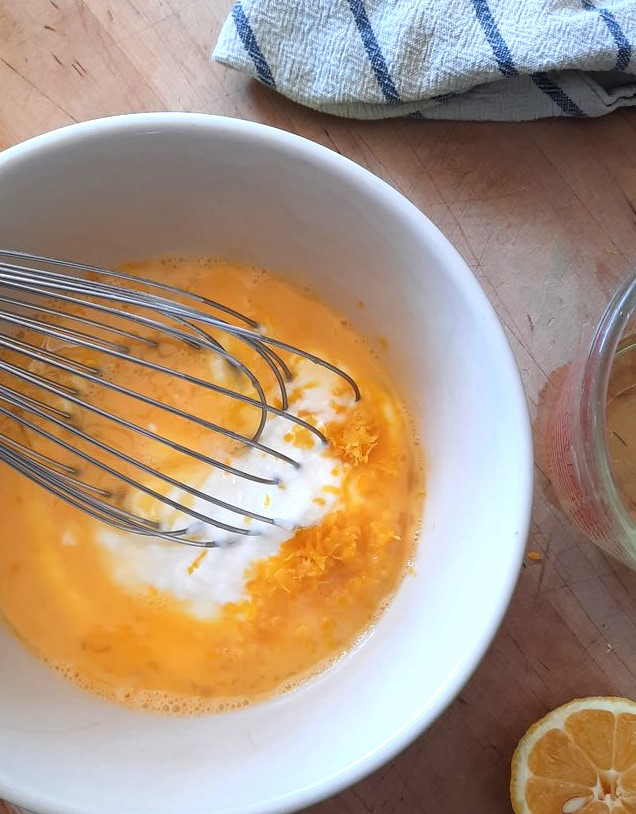 a whisk mixes wet ingredients for lemon blueberry coffee cake