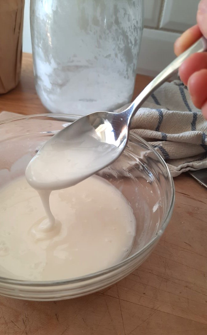 a spoon stirs lemon glaze until it is smooth