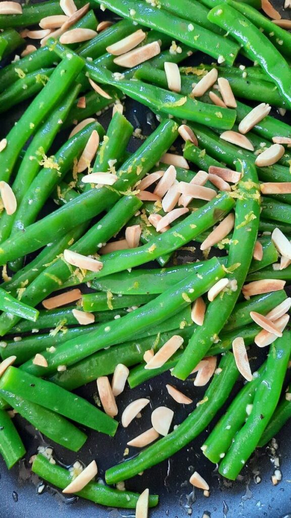 close up of green beans with garlic, almonds, and lemon