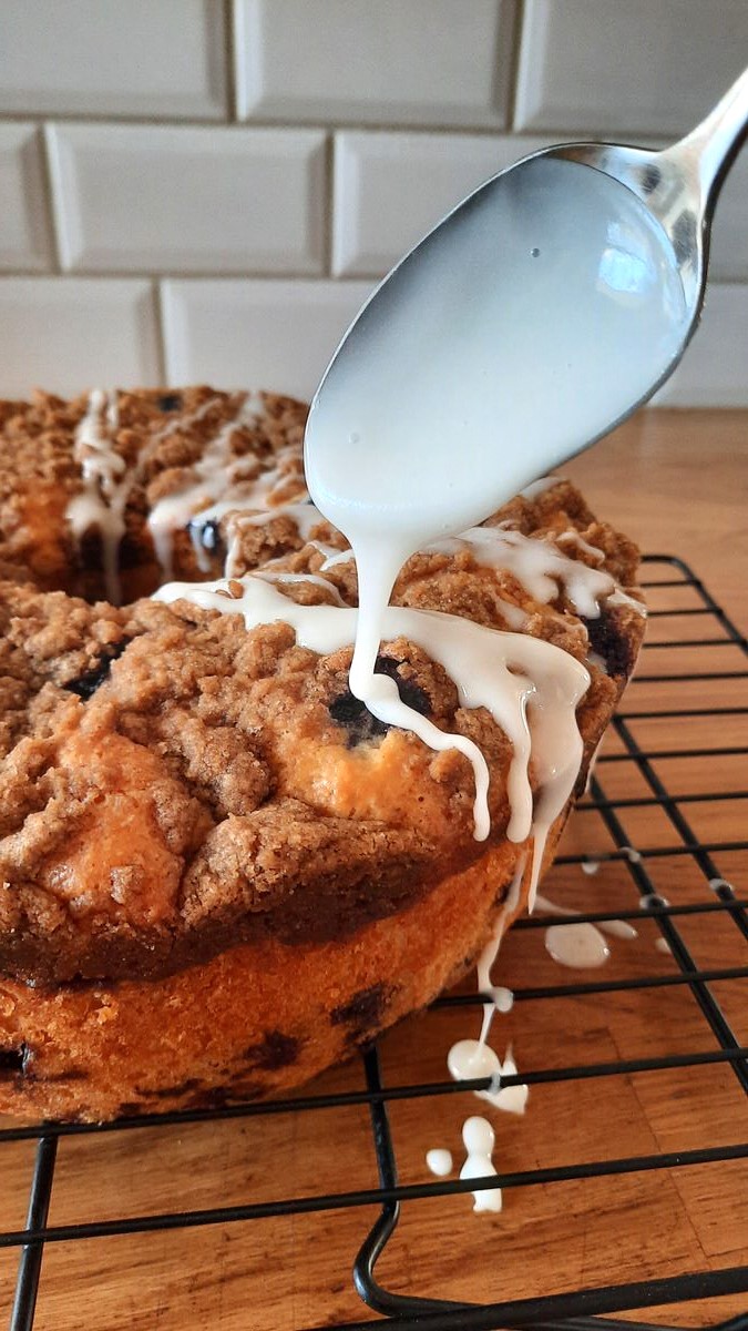 drizzling lemon glaze on to a cooled lemon blueberry coffee cake