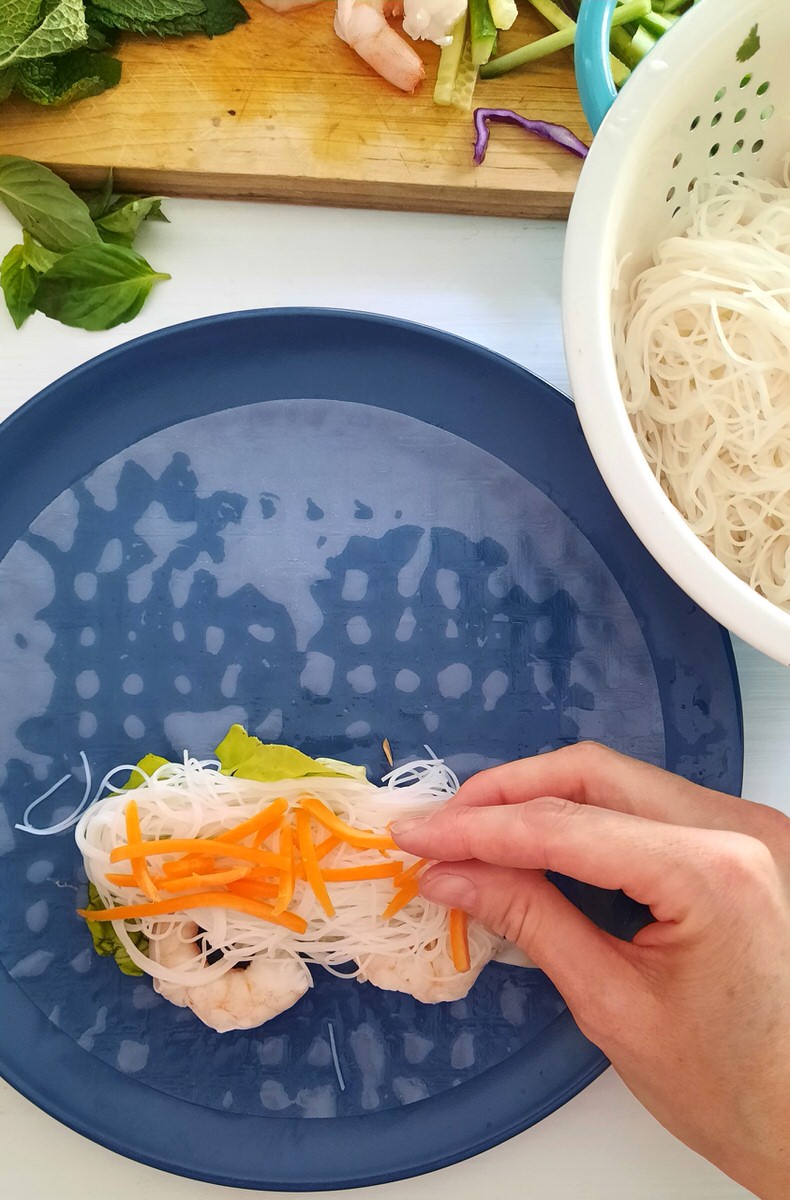 placing carrot cut into matchsticks on to a fresh spring roll