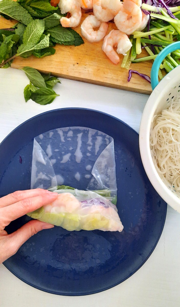 wrapping up a fresh spring roll on a blue plate