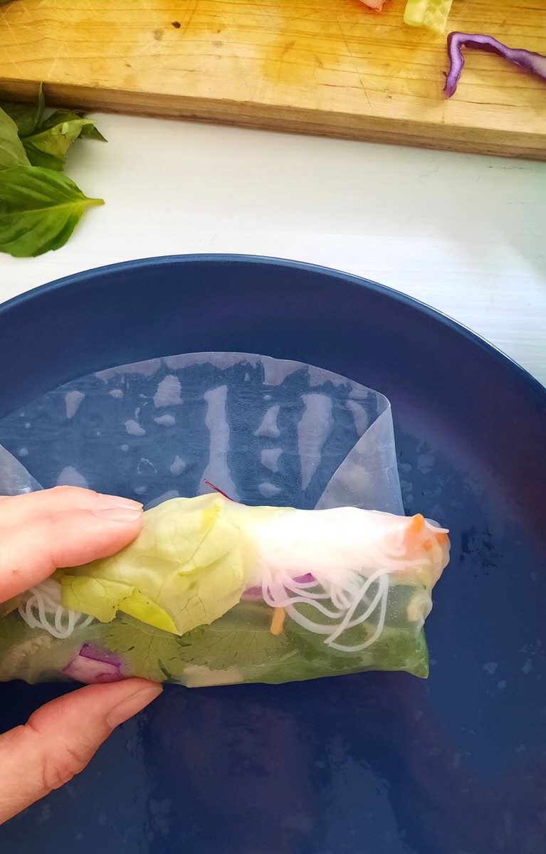 finishing wrapping a fresh spring roll on a plate