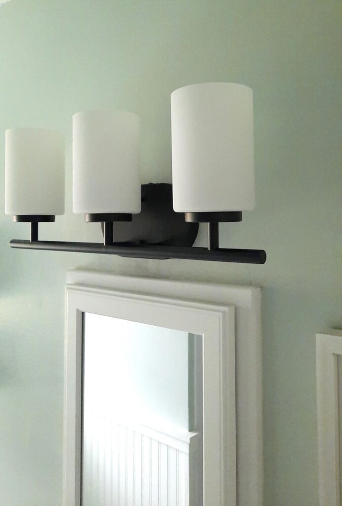 close up of bathroom vanity light fixture, black with frosted glass cylinders