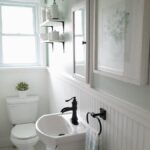 pretty soft green and white bathroom with black faucet and white beadboard