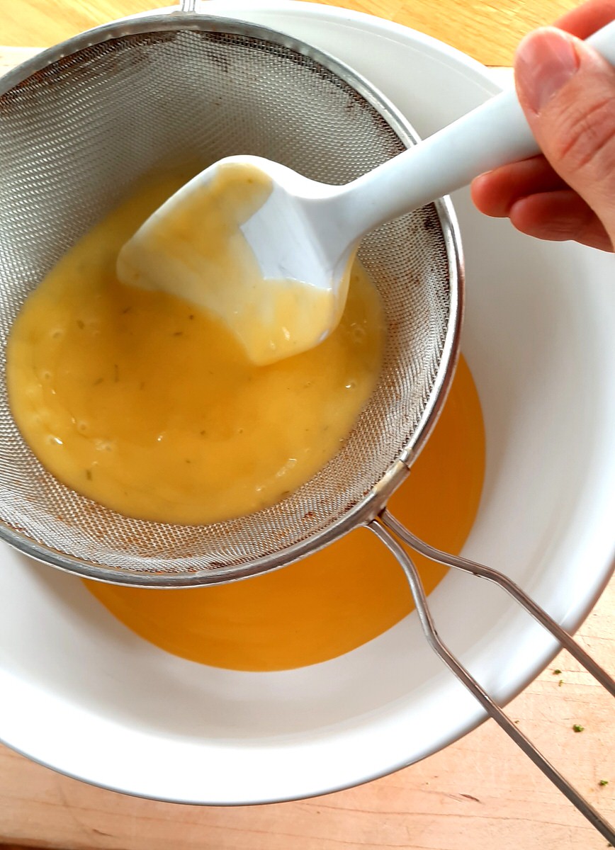 pressing cooked lime curd through a fine mesh strainer with a silicone spatula