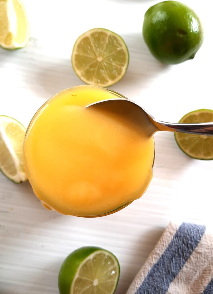 a spoon is dipped into a brimming jar of lime curd