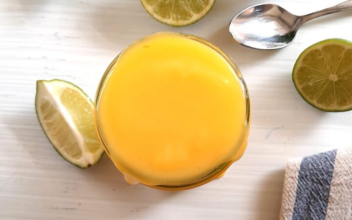 overflowing jar of fresh lime curd on a white counter, top view